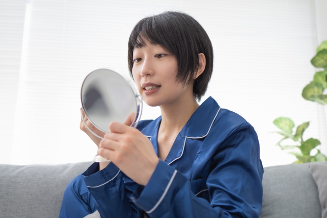 鏡で歯を見る女性の写真